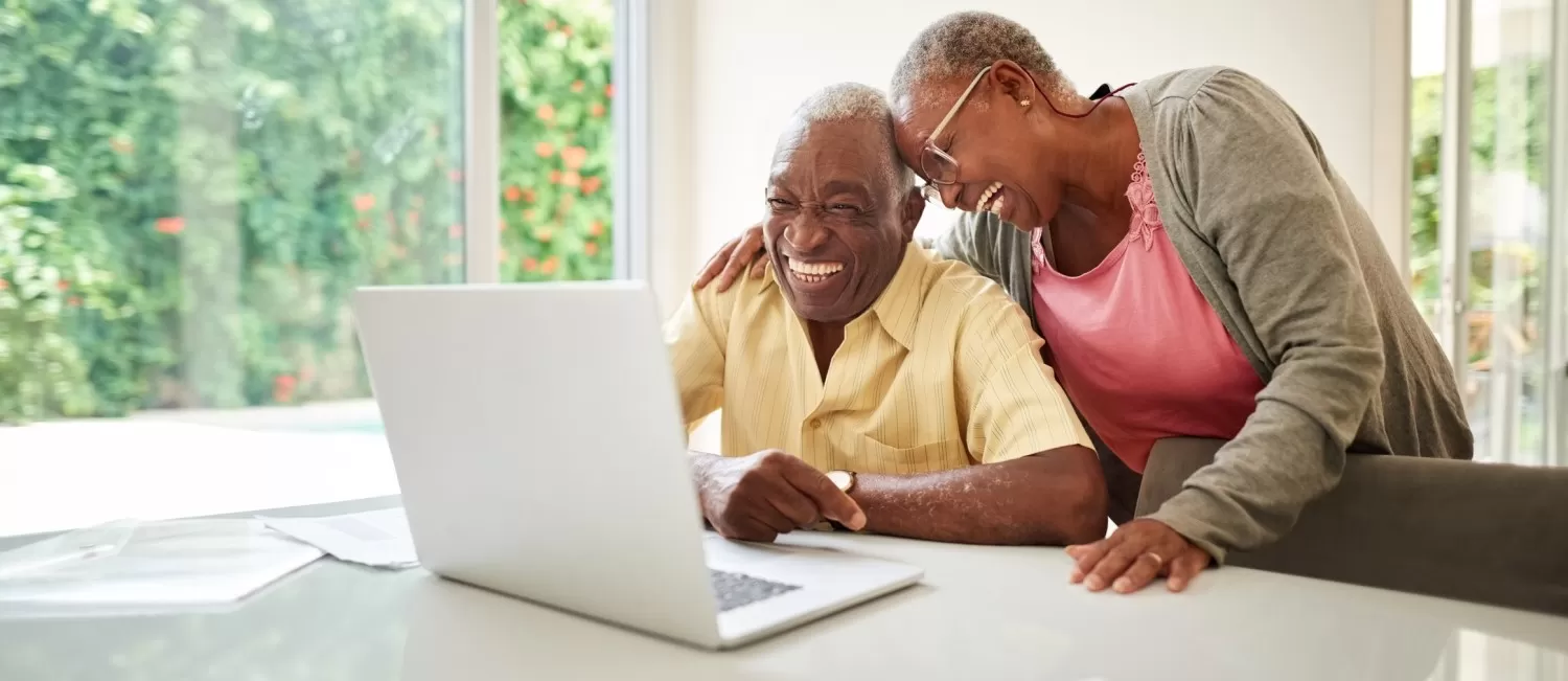 Homem e mulher sorrindo utilizando um notebook